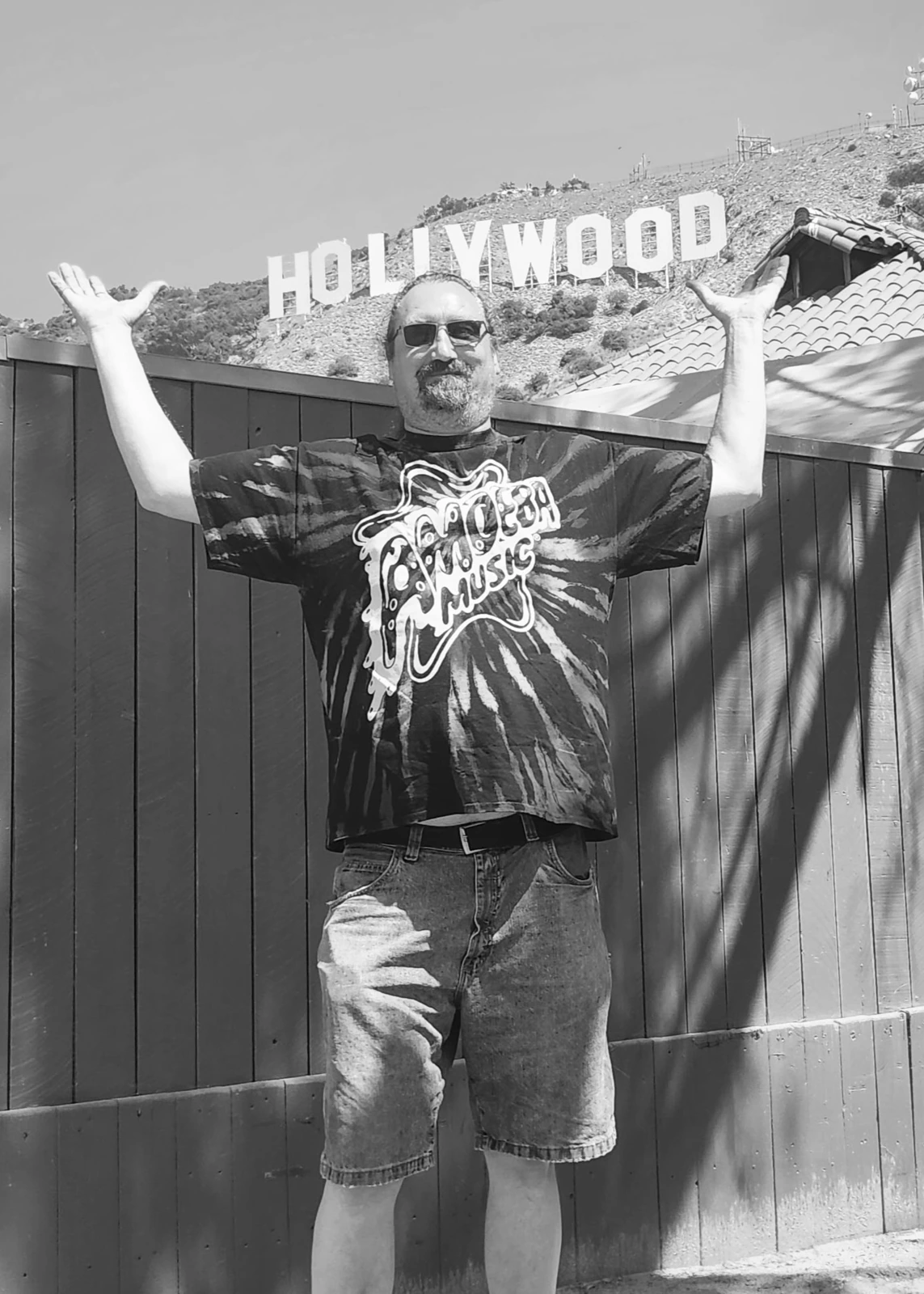 Band member raising his arms beneath the Hollywood sign